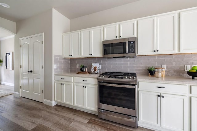 4604 Hibiscus Valley Dr, Austin, TX 78739 - kitchen with stainless steel appliances, light wood finished floors, backsplash, white cabinets, and light countertops