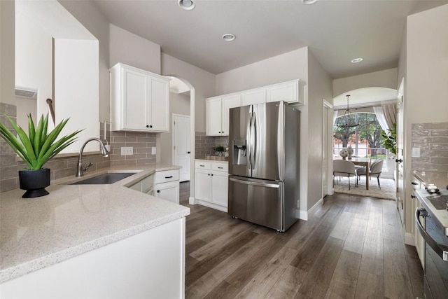 4604 Hibiscus Valley Dr, Austin, TX 78739 - kitchen with stainless steel appliances, arched walkways, light stone counters, dark wood finished floors, and white cabinetry