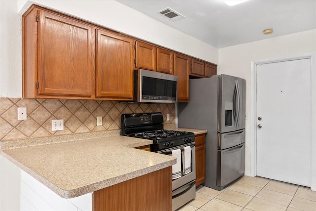 9400 Canus Dr, Austin, TX 78748 - kitchen featuring stainless steel appliances, light countertops, backsplash, brown cabinets, and a peninsula