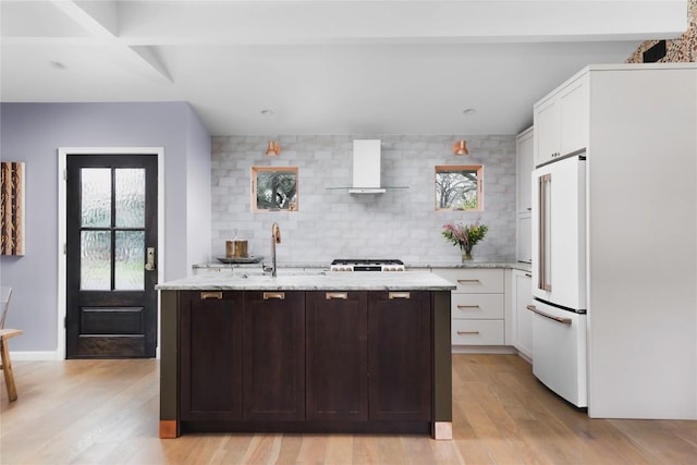 2410 W 9th St, Austin, TX 78703 - kitchen with high end white refrigerator, wall chimney exhaust hood, light wood-style floors, and white cabinetry
