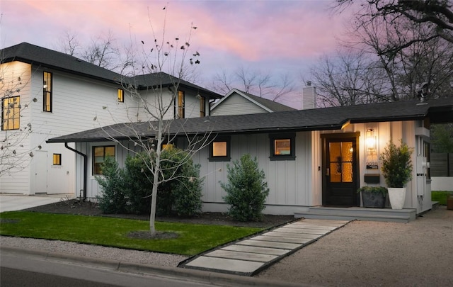 2410 W 9th St, Austin, TX 78703 - view of front of property with board and batten siding, a chimney, roof with shingles, and a front lawn