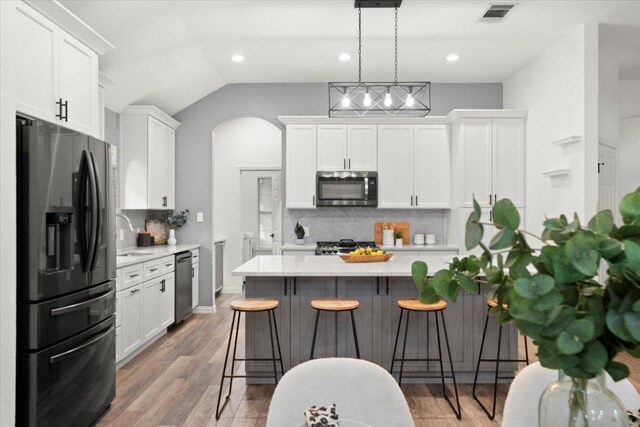 1522 Tamar Ln, Austin, TX 78727 - kitchen with stainless steel appliances, a breakfast bar area, white cabinets, backsplash, and recessed lighting