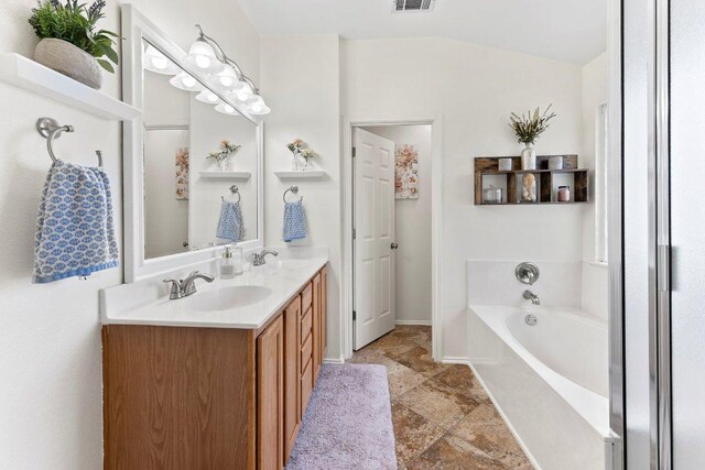 1401 Jackie Robinson Pl, Round Rock, TX 78665 - full bath featuring double vanity, a garden tub, lofted ceiling, and stone finish flooring