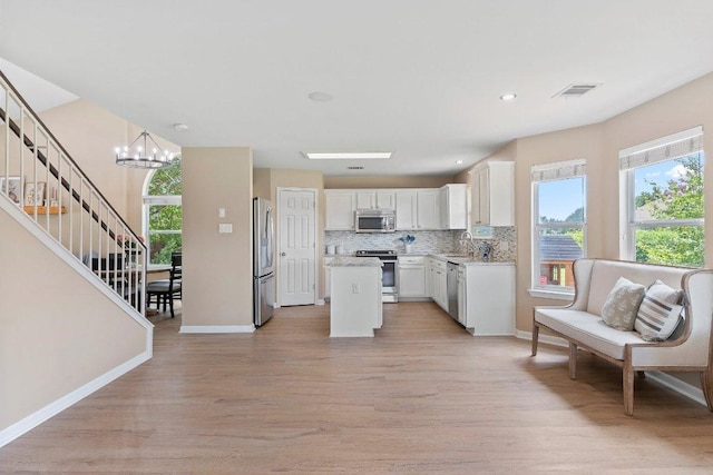 1401 Jackie Robinson Pl, Round Rock, TX 78665 - kitchen featuring appliances with stainless steel finishes, light wood-style floors, white cabinetry, decorative backsplash, and a kitchen island