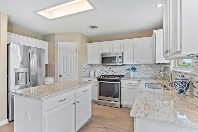 1401 Jackie Robinson Pl, Round Rock, TX 78665 - kitchen featuring appliances with stainless steel finishes, backsplash, white cabinetry, a center island, and light wood-style floors