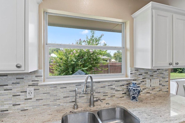 1401 Jackie Robinson Pl, Round Rock, TX 78665 - kitchen featuring decorative backsplash, white cabinetry, light stone countertops, and healthy amount of natural light