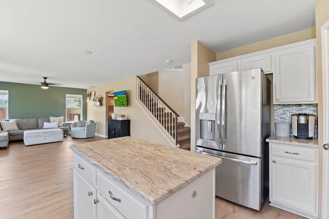 1401 Jackie Robinson Pl, Round Rock, TX 78665 - kitchen with stainless steel fridge, a center island, ceiling fan, white cabinetry, and light wood-style floors