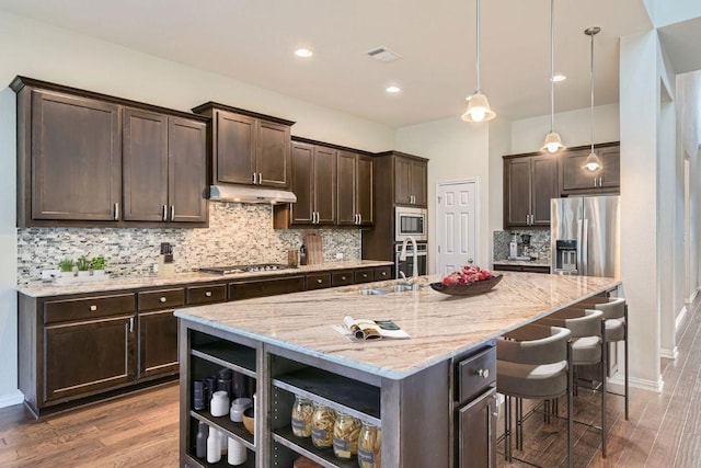 12383 Mesa Verde Dr, Austin, TX 78737 - kitchen featuring appliances with stainless steel finishes, dark brown cabinetry, open shelves, under cabinet range hood, and recessed lighting