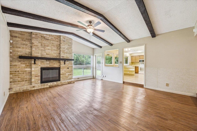 9613 Newberry Dr, Austin, TX 78729 - unfurnished living room featuring a ceiling fan, a fireplace, wood finished floors, and a textured ceiling