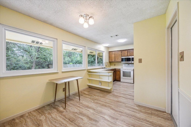 9613 Newberry Dr, Austin, TX 78729 - kitchen featuring stainless steel microwave, white electric stove, brown cabinetry, light wood-style flooring, and healthy amount of natural light
