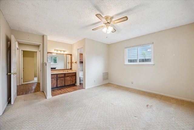 9613 Newberry Dr, Austin, TX 78729 - unfurnished bedroom featuring carpet, a textured ceiling, connected bathroom, and ceiling fan