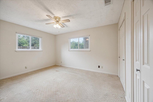 9613 Newberry Dr, Austin, TX 78729 - unfurnished bedroom with multiple windows, light colored carpet, a textured ceiling, and ceiling fan