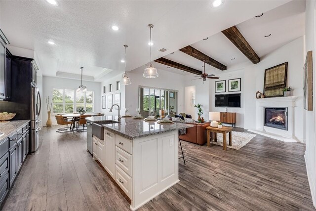 232 Cimarron Hills Trl E, Georgetown, TX 78628 - kitchen featuring dark wood finished floors, a warm lit fireplace, recessed lighting, light stone counters, and a center island with sink