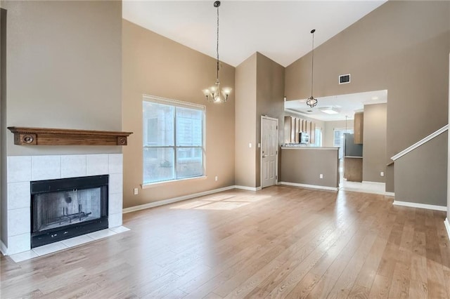 7500 Shadowridge Run Unit 47, Austin, TX 78749 - unfurnished living room featuring high vaulted ceiling, light wood finished floors, a chandelier, and a tiled fireplace