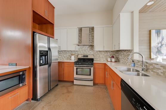 2822 Wooldridge Dr Unit B, Austin, TX 78703 - kitchen featuring appliances with stainless steel finishes, wall chimney range hood, backsplash, light countertops, and open shelves