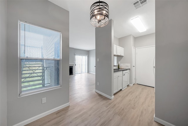 12166 Metric Blvd Unit 2011, Austin, TX 78758 - kitchen with light wood-style flooring, dark countertops, white cabinetry, and a fireplace