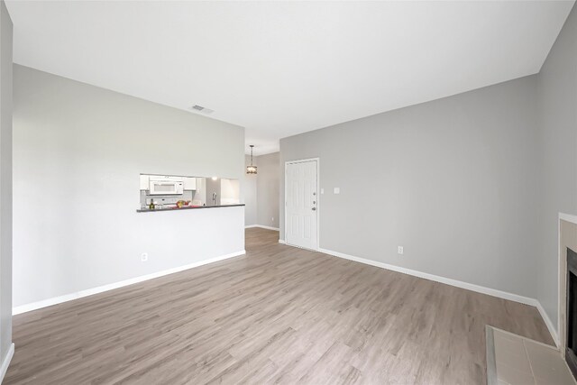12166 Metric Blvd Unit 2011, Austin, TX 78758 - unfurnished living room with light wood-style floors, a chandelier, and a fireplace with flush hearth