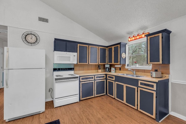 928 Moccasin Trl, La Grange, TX 78945 - kitchen with white appliances, lofted ceiling, light wood-style flooring, blue cabinets, and light countertops