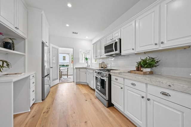 803 Jessie St, Austin, TX 78704 - kitchen with stainless steel appliances, white cabinets, open shelves, decorative backsplash, and light wood-style floors