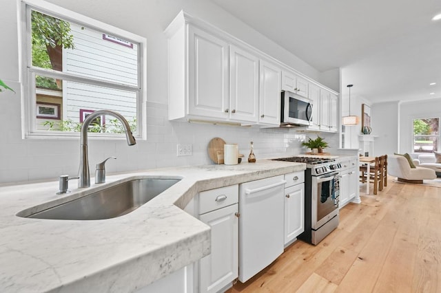 803 Jessie St, Austin, TX 78704 - kitchen featuring stainless steel appliances, white cabinets, backsplash, light wood-style flooring, and recessed lighting