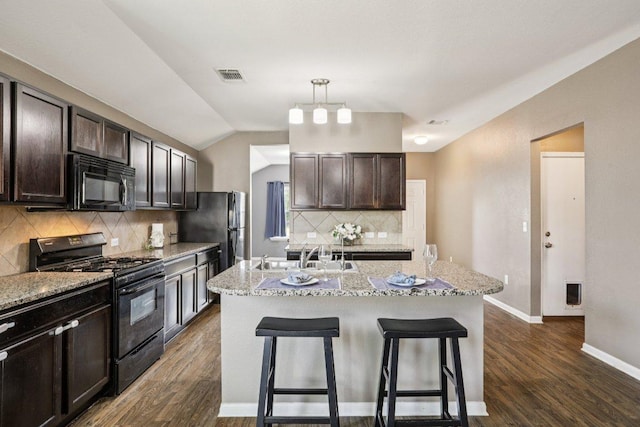 805 Red Tails Dr, Austin, TX 78725 - kitchen featuring black appliances, a kitchen bar, dark wood-style flooring, decorative backsplash, and vaulted ceiling
