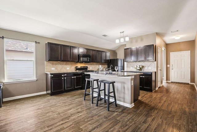 805 Red Tails Dr, Austin, TX 78725 - kitchen featuring black appliances, a kitchen bar, backsplash, dark wood finished floors, and dark brown cabinets