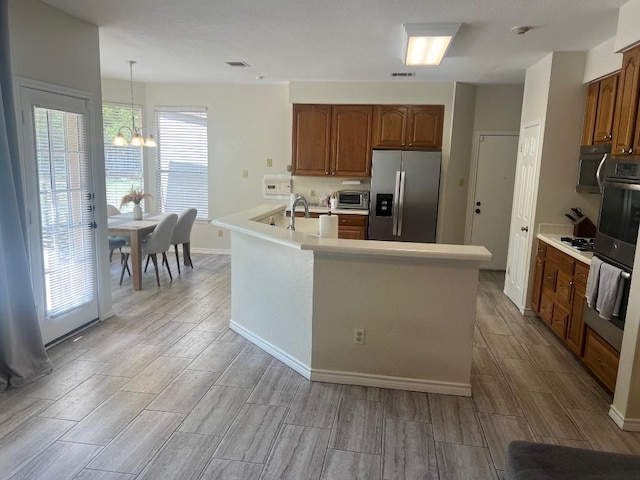 8104 Ephraim Rd, Austin, TX 78717 - kitchen with appliances with stainless steel finishes, wood finish floors, a chandelier, and brown cabinetry