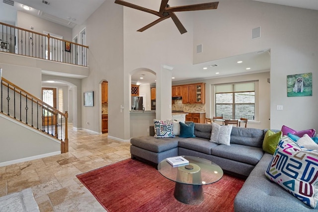6906 Covered Bridge Dr, Austin, TX 78736 - living area featuring arched walkways, a ceiling fan, a towering ceiling, stone tile floors, and stairway
