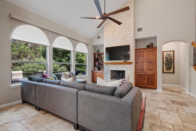 6906 Covered Bridge Dr, Austin, TX 78736 - living room featuring stone tile floors, a ceiling fan, high vaulted ceiling, a stone fireplace, and arched walkways