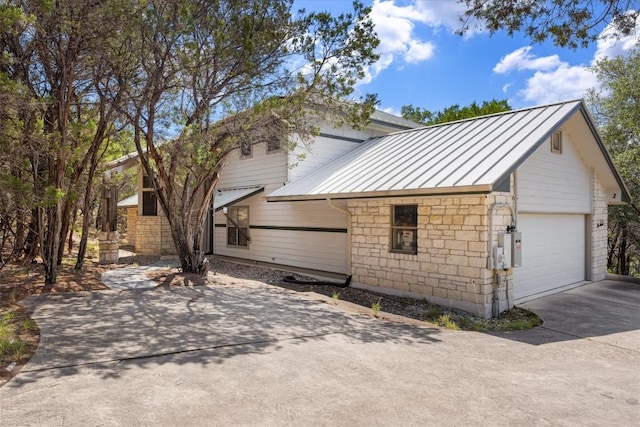 3805 Ranch Creek Dr, Austin, TX 78730 - view of home's exterior with a standing seam roof, a metal roof, stone siding, driveway, and a garage