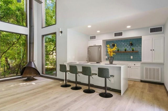 1135 Barton Hills Dr Unit 355, Austin, TX 78704 - kitchen featuring freestanding refrigerator, white cabinetry, light wood-style flooring, a wood stove, and recessed lighting