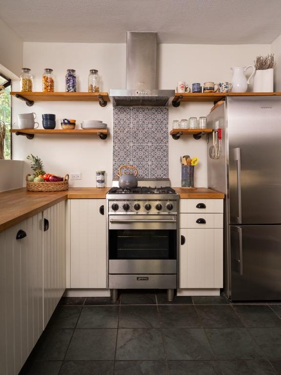 1005 E Riverside Dr, Austin, TX 78704 - kitchen featuring wall chimney range hood, appliances with stainless steel finishes, wood counters, and open shelves
