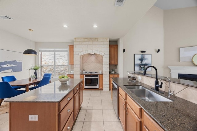 4009 Wilderness Path Bnd, Cedar Park, TX 78613 - kitchen featuring stainless steel appliances, a fireplace, backsplash, light tile patterned floors, and brown cabinets