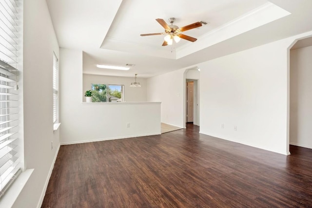 109 Onyx Lake Dr, Kyle, TX 78640 - empty room featuring arched walkways, a raised ceiling, dark wood-style flooring, a ceiling fan, and a chandelier