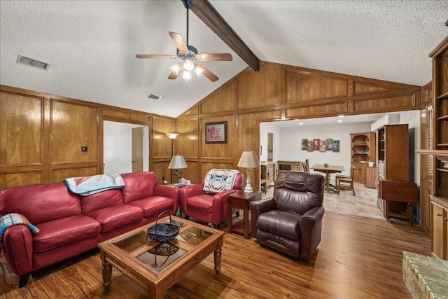 1601 Samoa Ct, Pflugerville, TX 78660 - living room featuring wood finished floors, a ceiling fan, wooden walls, beamed ceiling, and a textured ceiling
