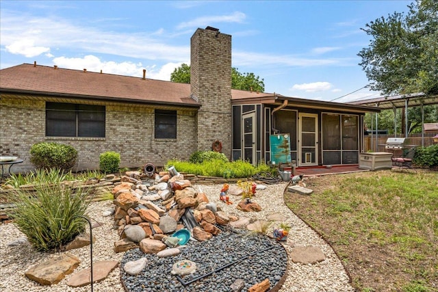 1601 Samoa Ct, Pflugerville, TX 78660 - rear view of house featuring a sunroom, a chimney, brick siding, and roof with shingles