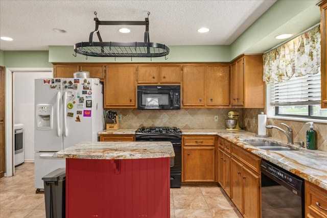 1601 Samoa Ct, Pflugerville, TX 78660 - kitchen featuring black appliances, brown cabinetry, a center island, a textured ceiling, and recessed lighting