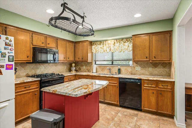 1601 Samoa Ct, Pflugerville, TX 78660 - kitchen featuring black appliances, brown cabinets, a kitchen island, a textured ceiling, and decorative backsplash
