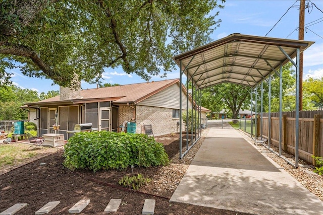 1601 Samoa Ct, Pflugerville, TX 78660 - view of home's exterior with a sunroom, brick siding, a chimney, and a detached carport