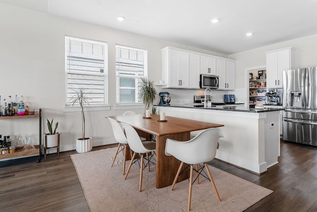3800 Bristol Motor Pass, Austin, TX 78728 - kitchen featuring stainless steel appliances, dark countertops, dark wood-style flooring, a peninsula, and white cabinetry
