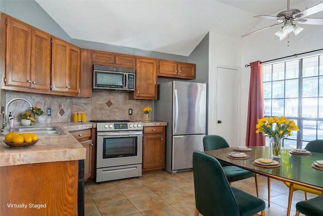 823 Topaz Ln, Leander, TX 78641 - kitchen featuring stainless steel appliances, lofted ceiling, light countertops, tasteful backsplash, and brown cabinets
