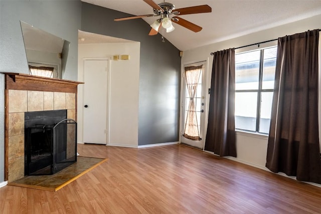 823 Topaz Ln, Leander, TX 78641 - unfurnished living room featuring lofted ceiling, wood finished floors, plenty of natural light, ceiling fan, and a tile fireplace