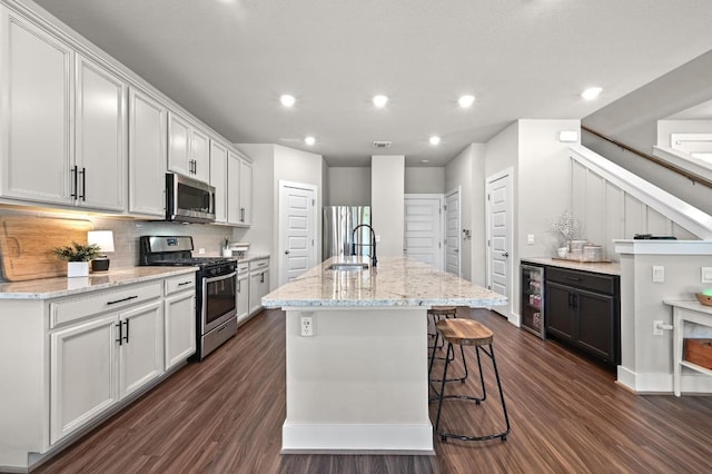 7506 Chesapeake Rail Ln, Austin, TX 78744 - kitchen featuring stainless steel appliances, dark wood finished floors, backsplash, a kitchen island with sink, and wine cooler