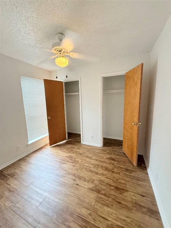 2803 Hemphill Park Unit B209, Austin, TX 78705 - unfurnished bedroom featuring multiple closets, wood finished floors, a textured ceiling, and ceiling fan