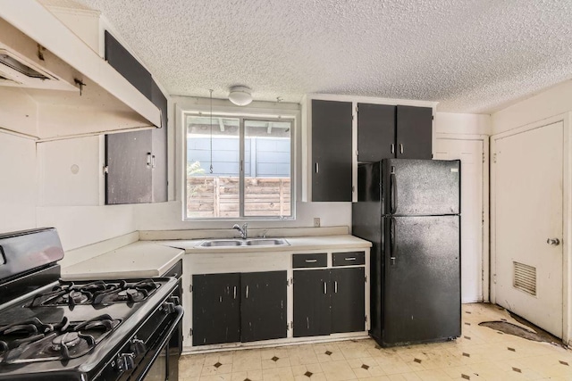 1611 Suffolk Dr, Austin, TX 78723 - kitchen featuring freestanding refrigerator, range with gas stovetop, under cabinet range hood, dark cabinetry, and a textured ceiling