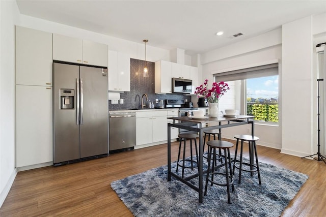 4361 S Congress Ave Unit 209, Austin, TX 78745 - kitchen featuring appliances with stainless steel finishes, tasteful backsplash, dark wood-type flooring, recessed lighting, and white cabinets