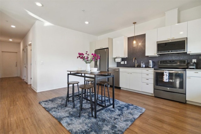 4361 S Congress Ave Unit 209, Austin, TX 78745 - kitchen featuring appliances with stainless steel finishes, backsplash, wood finished floors, and recessed lighting