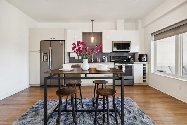 4361 S Congress Ave Unit 209, Austin, TX 78745 - kitchen featuring appliances with stainless steel finishes, tasteful backsplash, dark wood finished floors, and pendant lighting