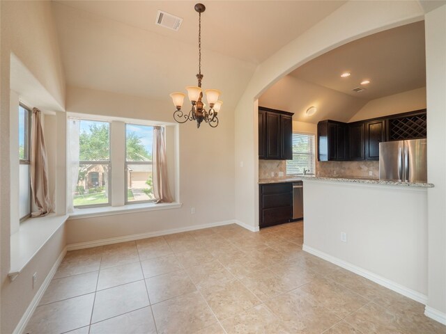 457 Monahans Dr, Georgetown, TX 78628 - kitchen featuring appliances with stainless steel finishes, vaulted ceiling, tasteful backsplash, a chandelier, and light stone counters