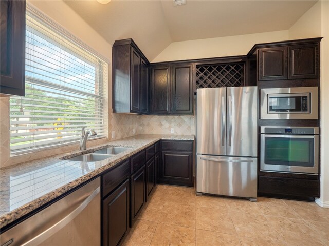 457 Monahans Dr, Georgetown, TX 78628 - kitchen with stainless steel appliances, light stone countertops, backsplash, lofted ceiling, and dark brown cabinets